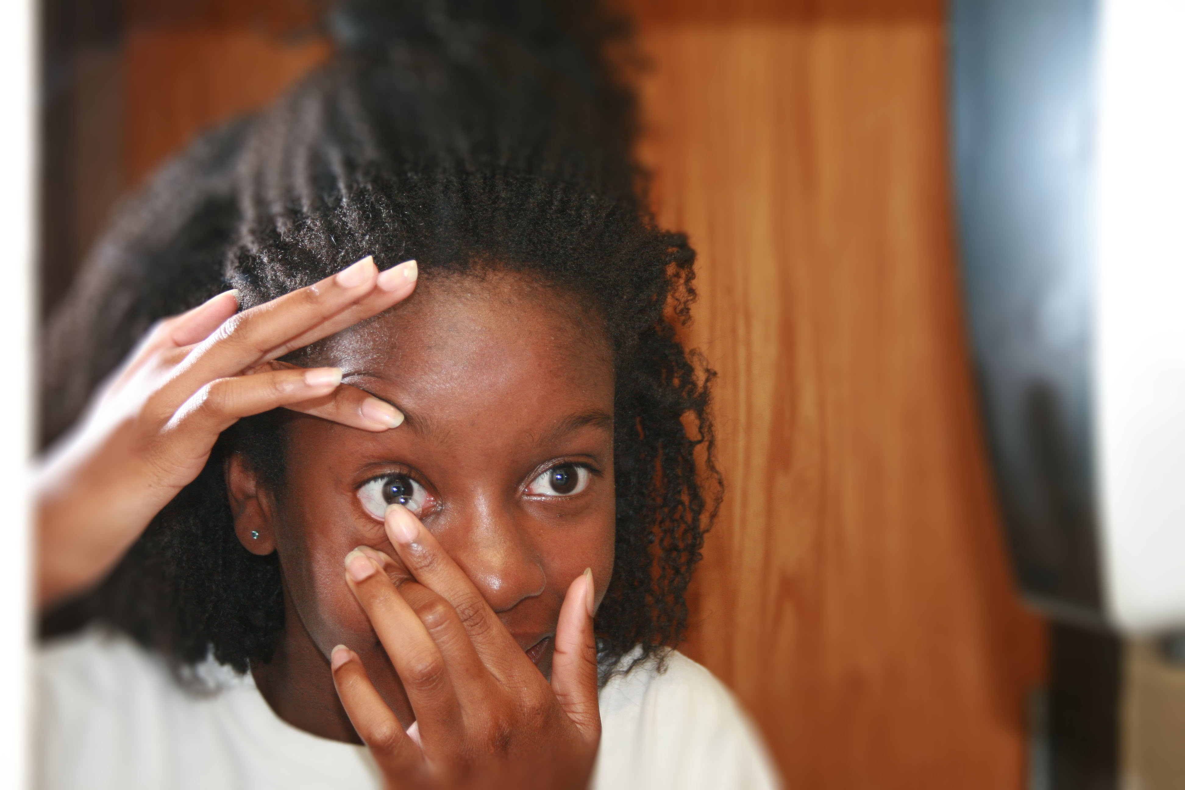 Teen girl inserting contact lens